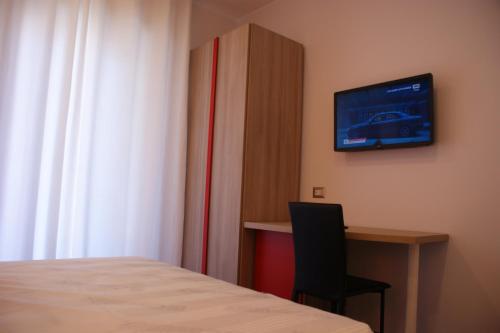 ナポリにあるB&B Isole - Rione altoのベッドと机とテレビのある部屋