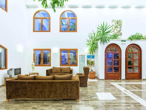 a living room with brown couches and windows at Hotel Europa Olympia in Olympia