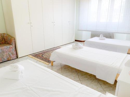 a white room with two beds and a chair at Cuore di Nozzano Castello in Lucca