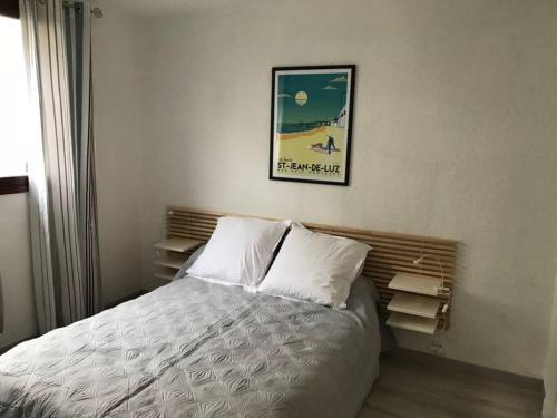 łóżko w sypialni z obrazem na ścianie w obiekcie AICE HEGOA avec Parking Inclus w mieście Saint-Jean-de-Luz
