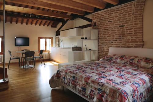 a bedroom with a bed and a kitchen and a table at Loft Mirano Due (Alloggi alla Campana) in Mirano