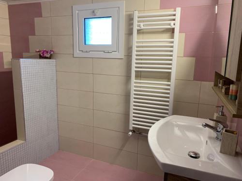 a bathroom with a sink and a toilet and a window at Peaceful house near Airport in Pikérmion