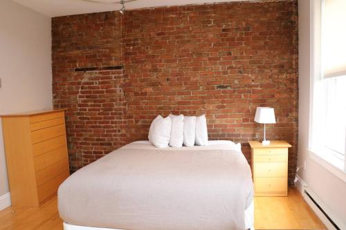 1 dormitorio con pared de ladrillo y cama con almohadas en Stylish Downtown Studio in the South End, #8 en Boston
