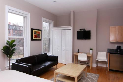 a living room with a black leather couch and a table at Stylish Downtown Studio in the South End, #8 in Boston