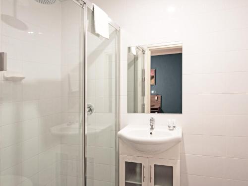 a bathroom with a shower, sink, and mirror at 28 Hotel in Sydney