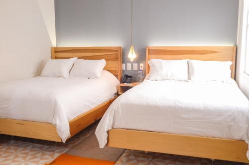 zwei Betten in einem Zimmer mit weißen Laken in der Unterkunft Casa Nuevo Leon in Mexiko-Stadt