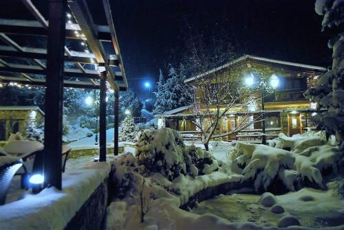 a house covered in snow at night with lights at Tzivaeri in Likodhrómion