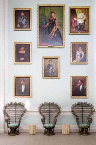 a wall with portraits of people on a wall with chairs at Queen Kapiolani Hotel in Honolulu