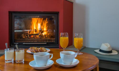 a table with two glasses of orange juice and a fireplace at Pirrion Wellness Boutique Hotel in Ano Pedina
