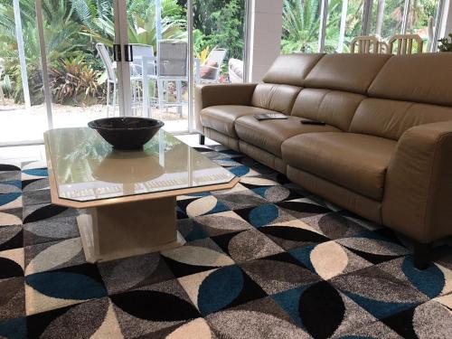 a living room with a couch and a glass table at Ancient Gardens Guesthouse & Botanical Gardens in Eudlo