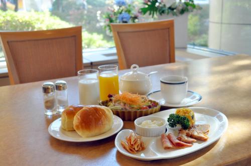 a table with two plates of breakfast foods and orange juice at Hotel Sapporo Sun Plaza in Sapporo