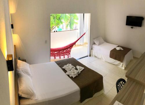 a hotel room with two beds and a balcony at Pousada Paraíso Maragogi in Maragogi