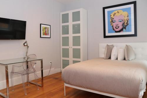 a bedroom with a bed with a desk and a television at A Stylish Stay w/ a Queen Bed, Heated Floors.. #21 in Brookline
