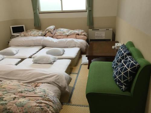 a room with several beds and a desk and a table at Lodge Christmas Rose Zao in Zao Onsen
