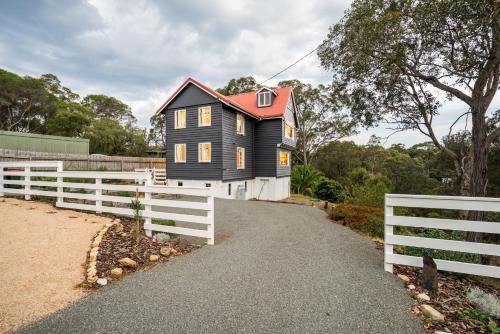 a black house with a white fence next to it at The Oar House in Metung