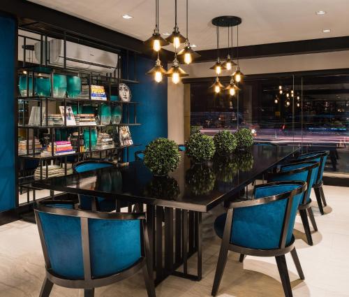 une salle à manger avec une table noire et des chaises bleues dans l'établissement Astoria Greenbelt, à Manille