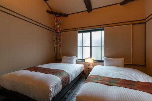 two beds in a room with a window at Mimari Machiya House in Kanazawa
