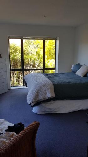 a bedroom with a large bed and a large window at Tranquil Treehouse in Christchurch