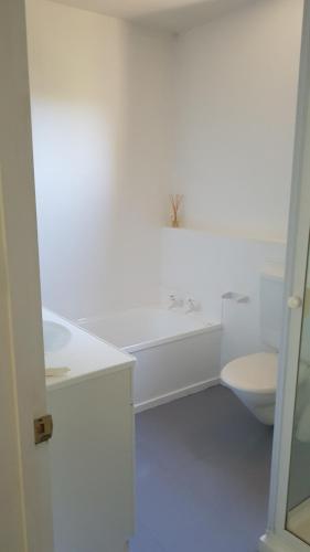 a white bathroom with a tub and a toilet at Tranquil Treehouse in Christchurch