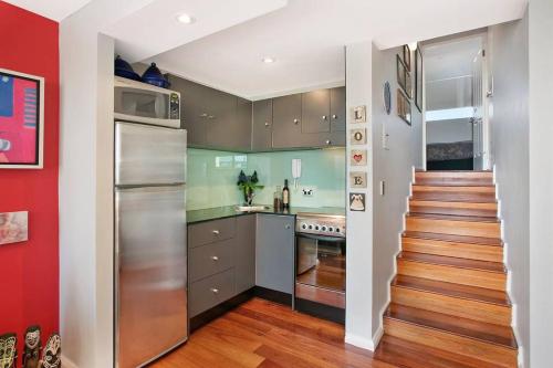 a kitchen with stainless steel appliances and a red wall at manlybeachonline.com713 At The Beach in Sydney