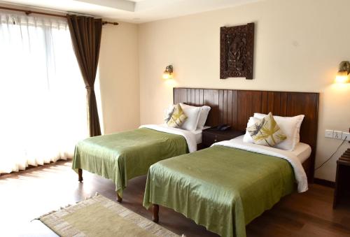 Habitación de hotel con 2 camas con sábanas verdes en Hotel Excelsior, en Katmandú