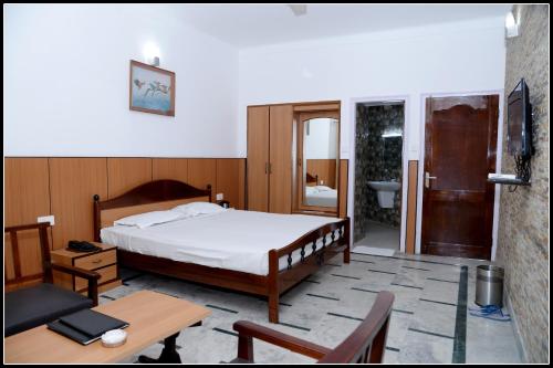 a bedroom with a bed and a table and a bathroom at Hotel Valley View in Mandi