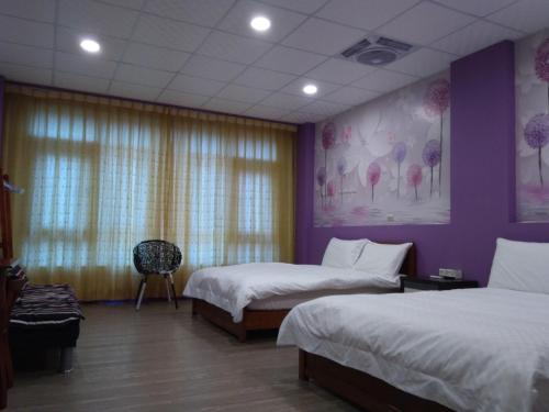 a bedroom with two beds and a purple wall at Grapefruit Heping Guesthouse in Hualien City