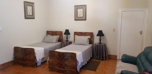 sala de estar con 2 camas y sofá en Upper Houghton Guesthouse, en Johannesburgo