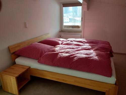 ケセンにあるApartment Schinterwinklのベッドルーム1室(赤い掛け布団、窓付)