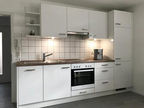 a white kitchen with white cabinets and a sink at Souterrain Ferienwohnung im Acherner Weg in Achern