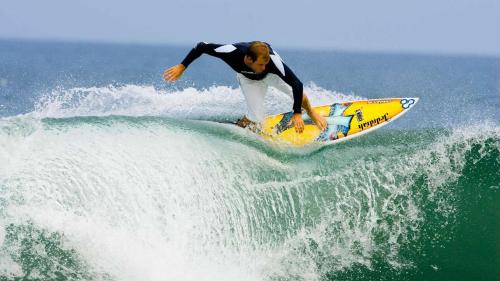 a man riding a wave on a surfboard in the ocean at Izu Hokkawa Seaside Guesthouse 伊豆北川の家 in Higashiizu