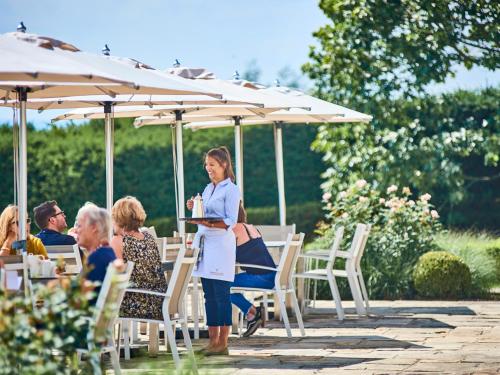 a woman standing under an umbrella at a table at Walwick Hall Country Estate and Spa in Hexham