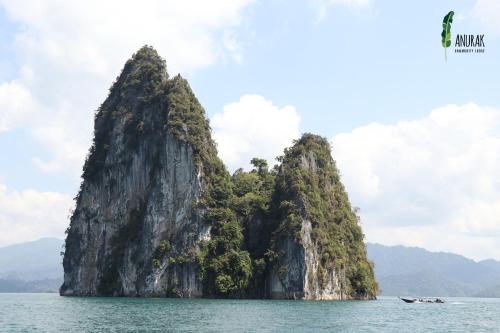 a rocky island in the water with a boat at Anurak Community Lodge - SHA Plus in Khao Sok