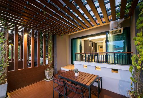a patio with a wooden table and chairs on a balcony at Nadee 10 Resort & Hotel in Khon Kaen