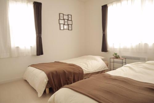 1 Schlafzimmer mit 2 Betten und einem Fenster in der Unterkunft Bayside in Hakodate