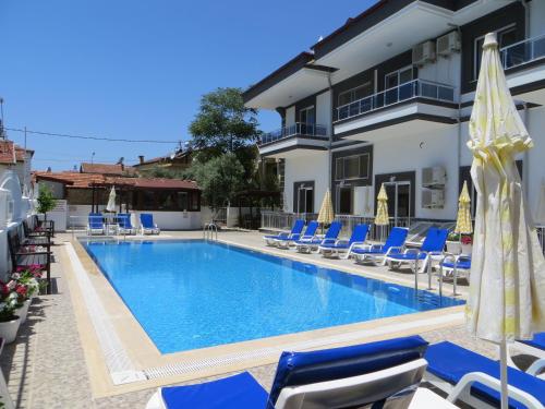 a swimming pool with chairs and umbrellas next to a building at Stella City Apartments in Fethiye