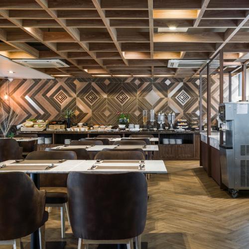 a restaurant with wooden ceilings and tables and chairs at Zayn Hotel Bangkok - Airport Link Access in Bangkok