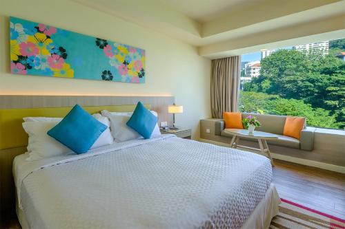 a bedroom with a bed, a desk and a painting on the wall at Mercure Penang Beach in George Town