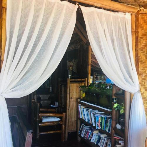 a room with a curtain and a book shelf with books at Camiguin Blue Lagoon Cottages in Mahinog
