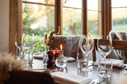 a table with wine glasses and a candle on it at The Duncombe Arms in Ellastone