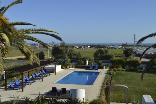 - une piscine avec des chaises longues bleues à côté d'un complexe dans l'établissement Tavira Vacations Apartments, à Tavira