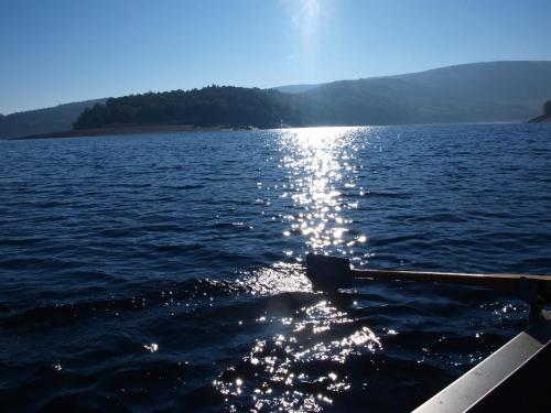 a boat in the water with the sun reflecting on the water at Hotel Haus Seeblick in Nideggen