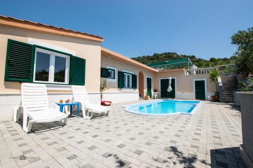 a patio with two chairs and a swimming pool at Summer rental house "Kava" in Okrug Donji