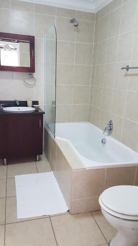 a bathroom with a tub and a toilet and a sink at Innes Road Durban Accommodation 2 bedroom private unit in Durban