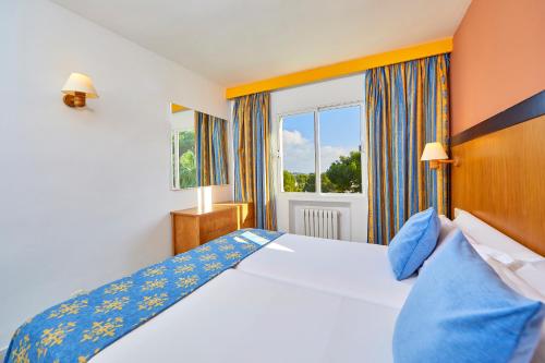 a bedroom with a bed and a large window at Gavimar La Mirada Hotel and Apartments in Cala d´Or