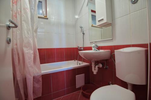 a bathroom with a sink and a toilet and a bath tub at Apartments & rooms Leon in Neum