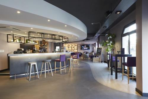 un bar en un restaurante con taburetes púrpura en Campanile Blanc-Mesnil en Le Blanc-Mesnil