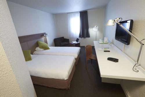 a hotel room with two beds and a desk at Campanile Blanc-Mesnil in Le Blanc-Mesnil