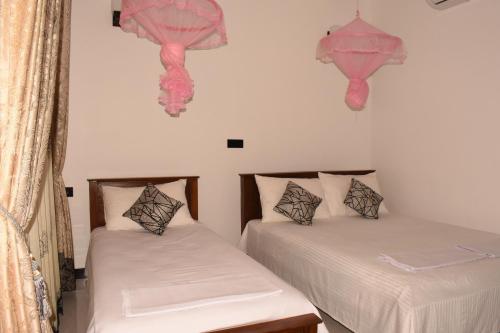 - 2 lits dans une chambre avec des décorations roses sur le mur dans l'établissement Sea Zone Hotel Nilaveli, à Nilaveli