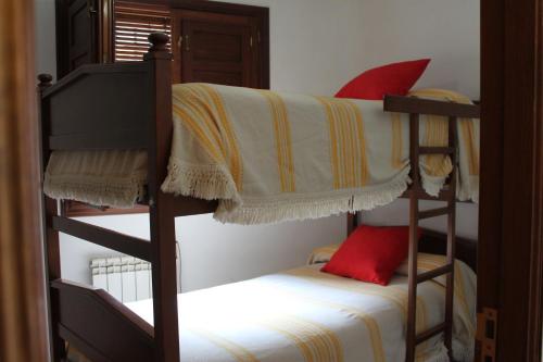 a bedroom with two bunk beds with red pillows at Apartamentos Rurales Rosendo: El Azahar in Capileira
